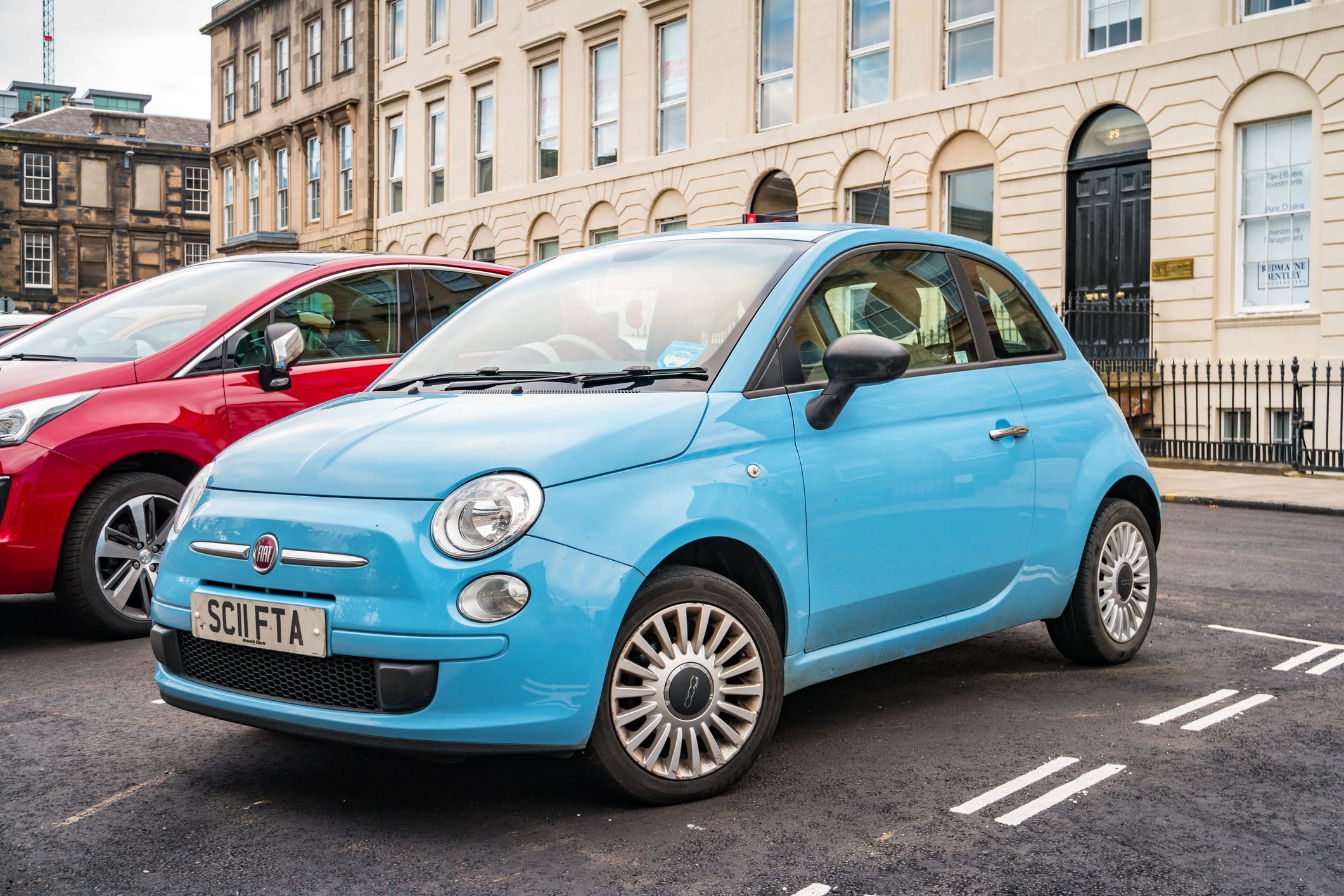 Blue Fiat 500 parked on the road.